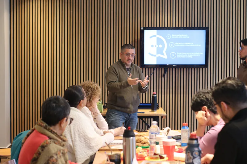 Estudiantes y coaches sentados en mesas durante un encuentro de NP+
